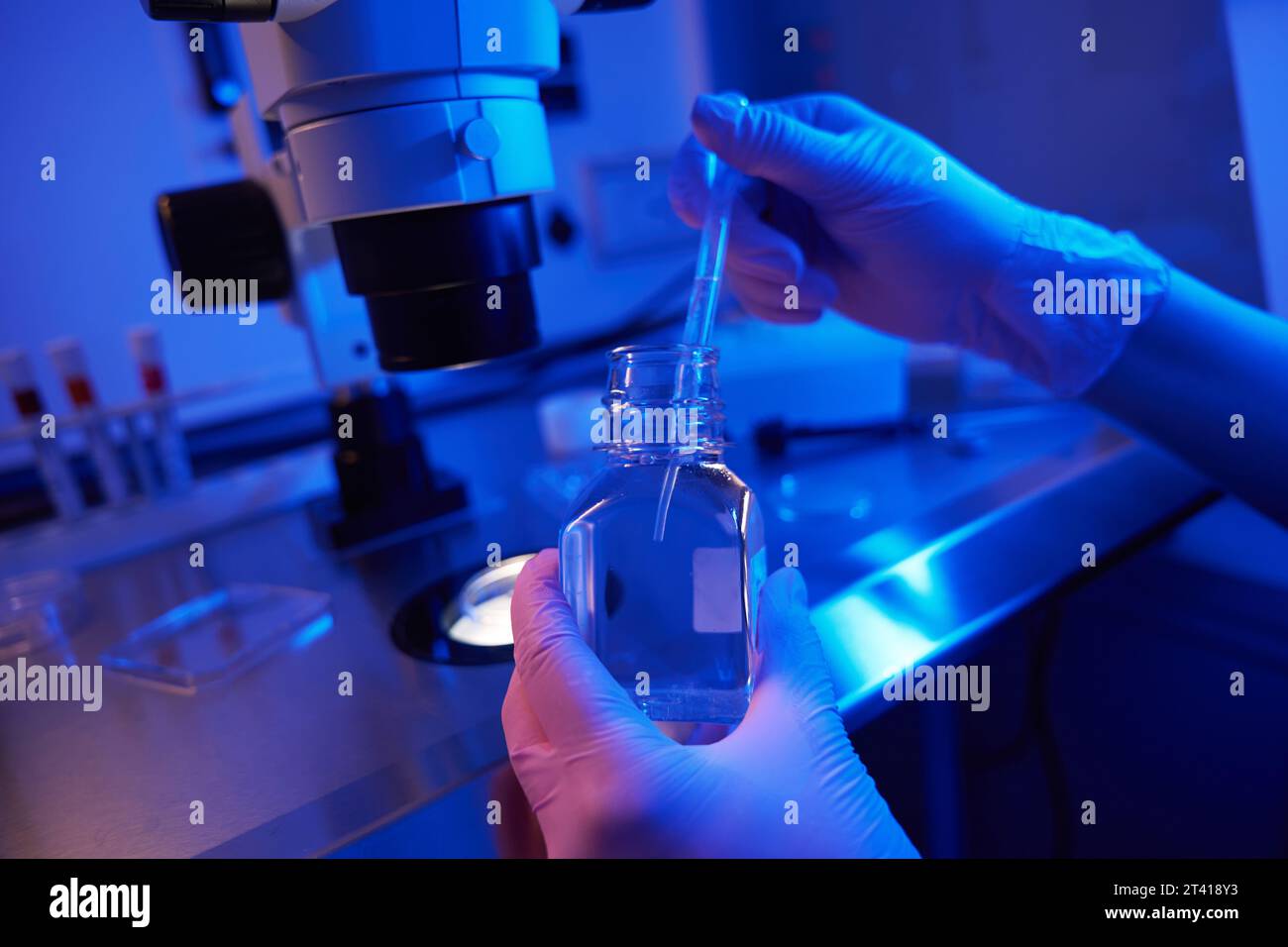 Lab scientist aspirating liquid with Pasteur pipette from reagent