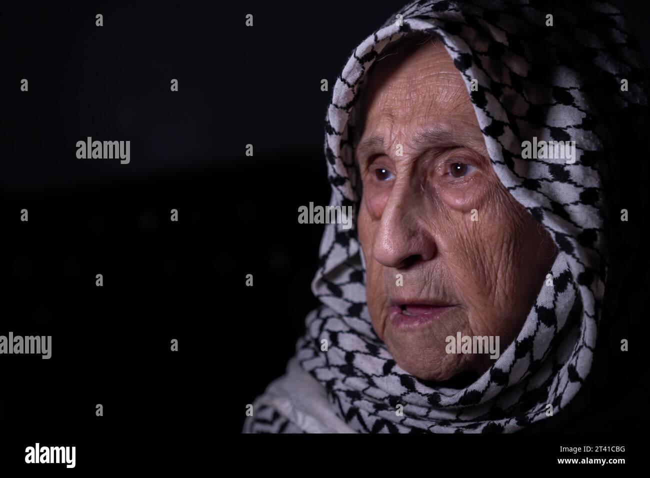 portrait of an old lady in dark background wearing white palestinian ...