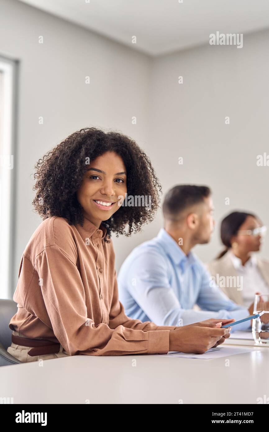 Vertical portrait of happy young African business woman at office meeting. Stock Photo