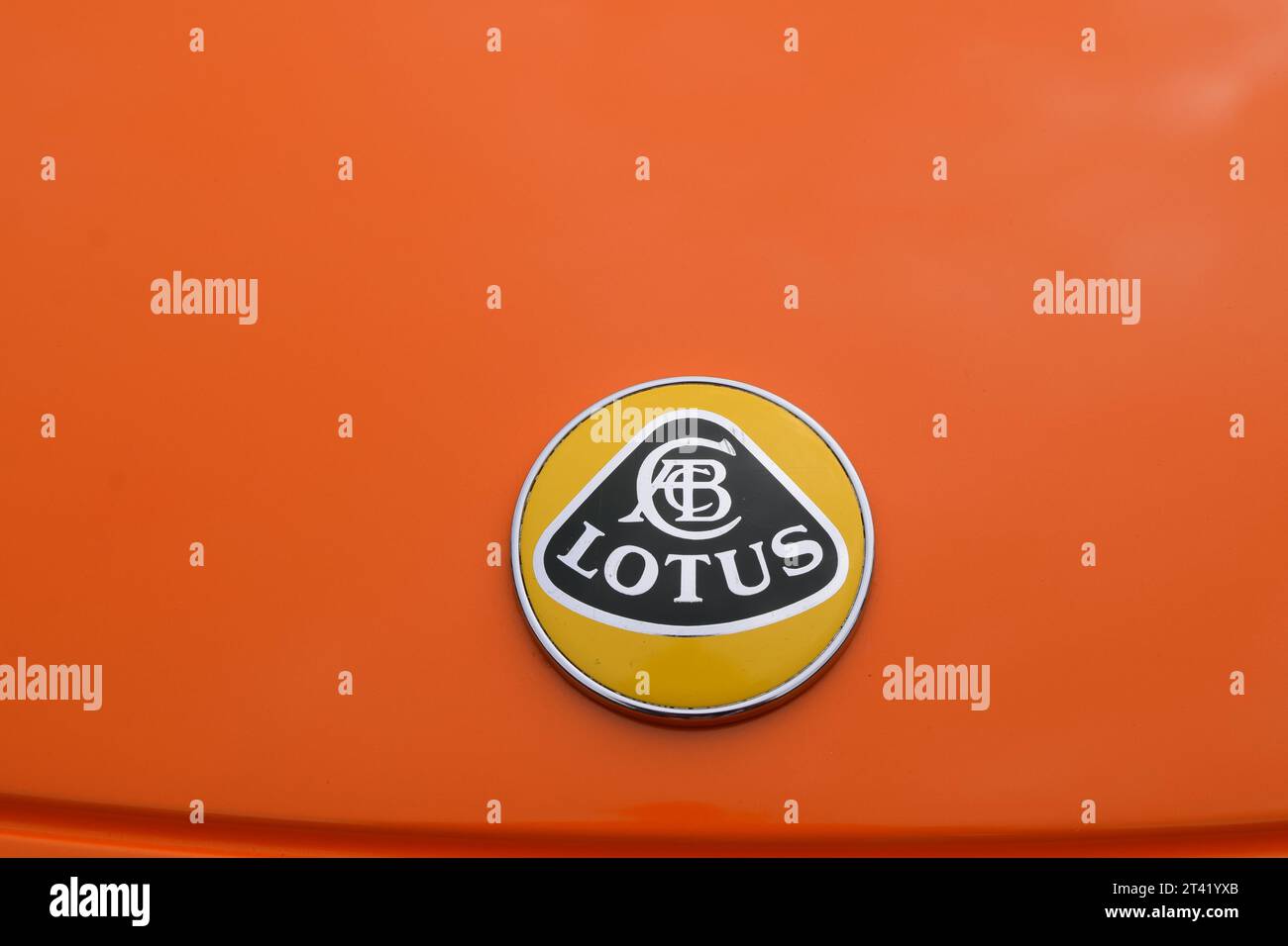 An orange automobile featuring a Lotus badge on the rear trunk of the ...