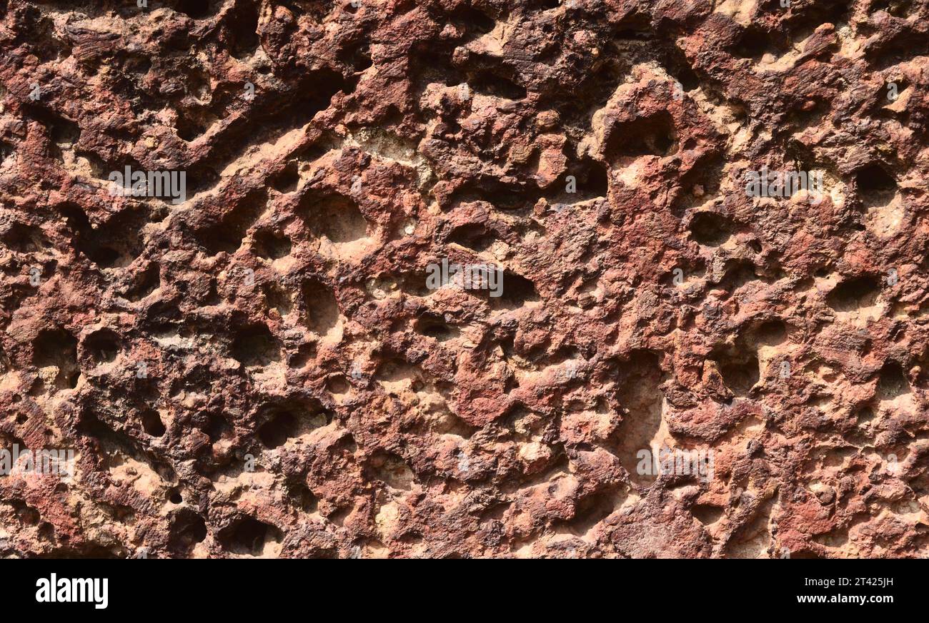 Many holes on the brown with orange and red color surface of the old laterite rock Stock Photo