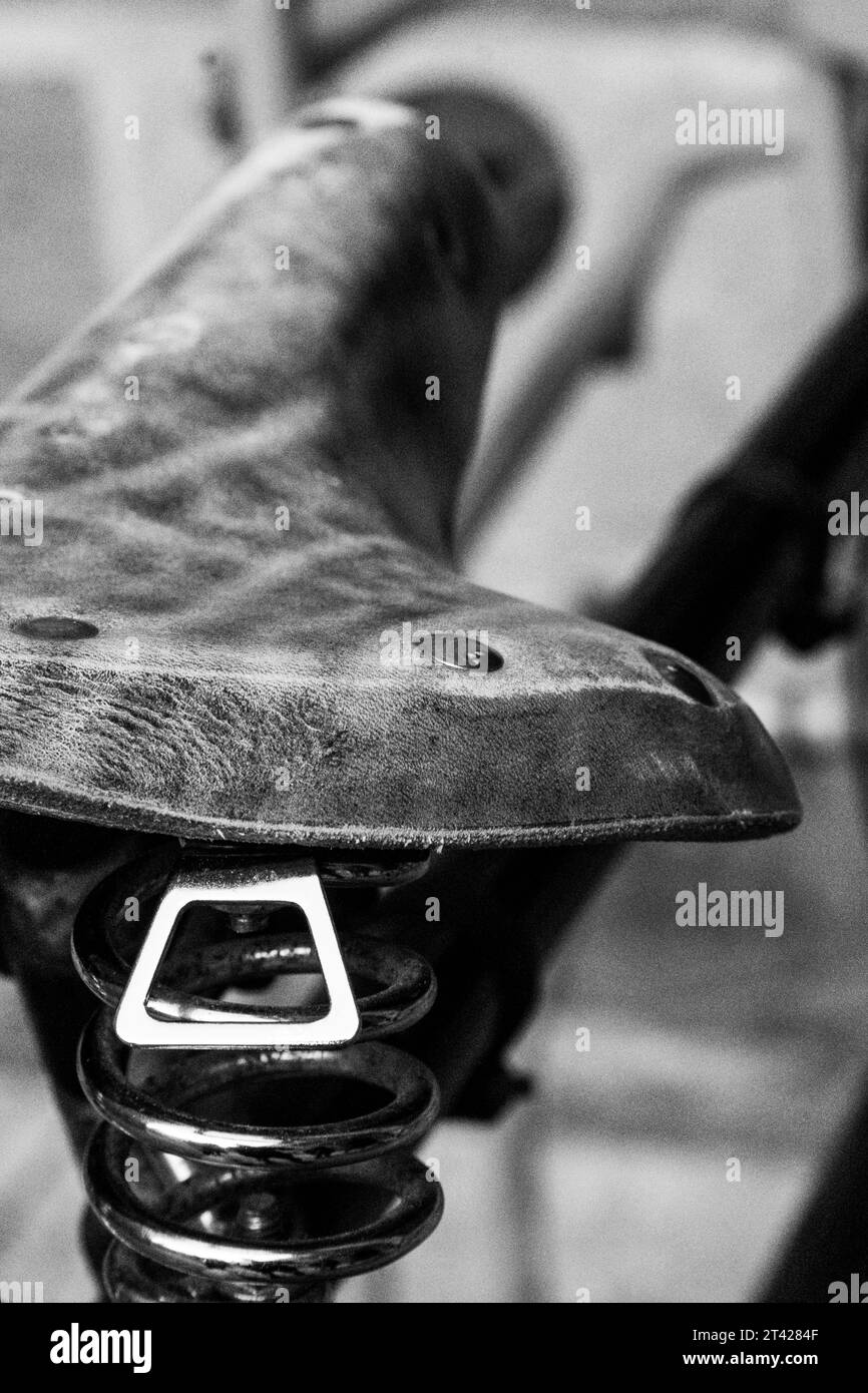 A closeup of an aged bicycle seat on a metal rod with coiled springs