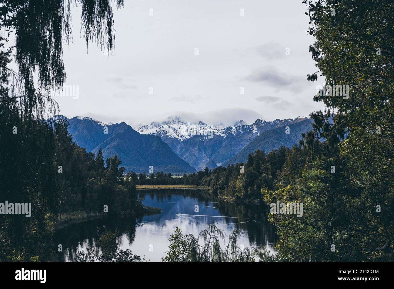 A tranquil lake surrounded by lush evergreen trees with majestic snow ...