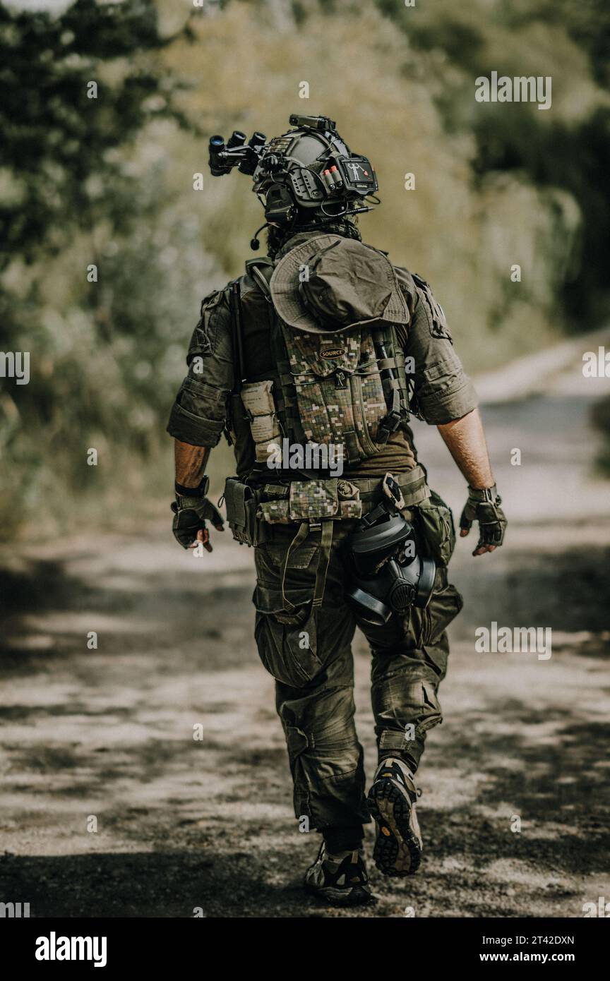A Caucasian male dressed in a full military uniform stands with a backpack on his back Stock Photo