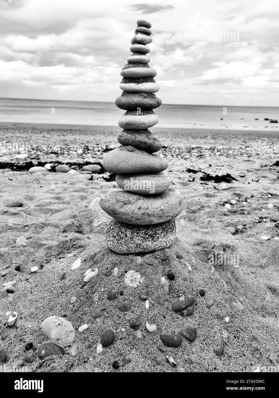 A scenic landscape of a beach with a stack of rocks in the foreground