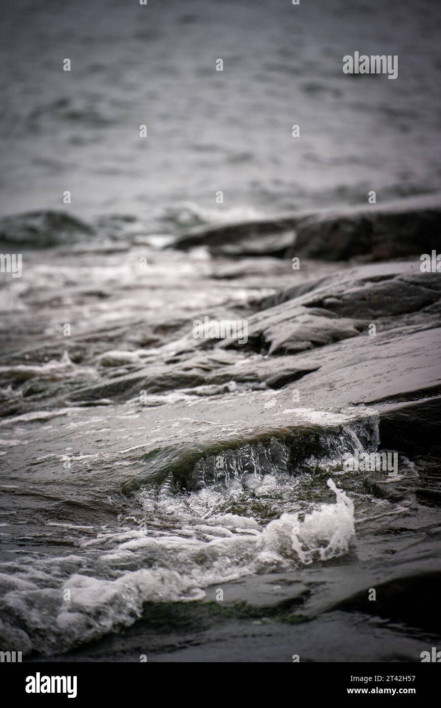 A high-contrast black and white image of powerful waves crashing onto a ...