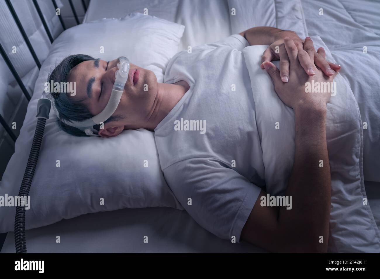 Happy and healthy Asian man wearing Cpap mask sleeping smoothly in bed