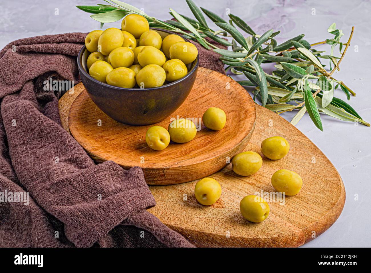 A wooden board with an array of ripe green Manzanilla Olives and other decorations Stock Photo