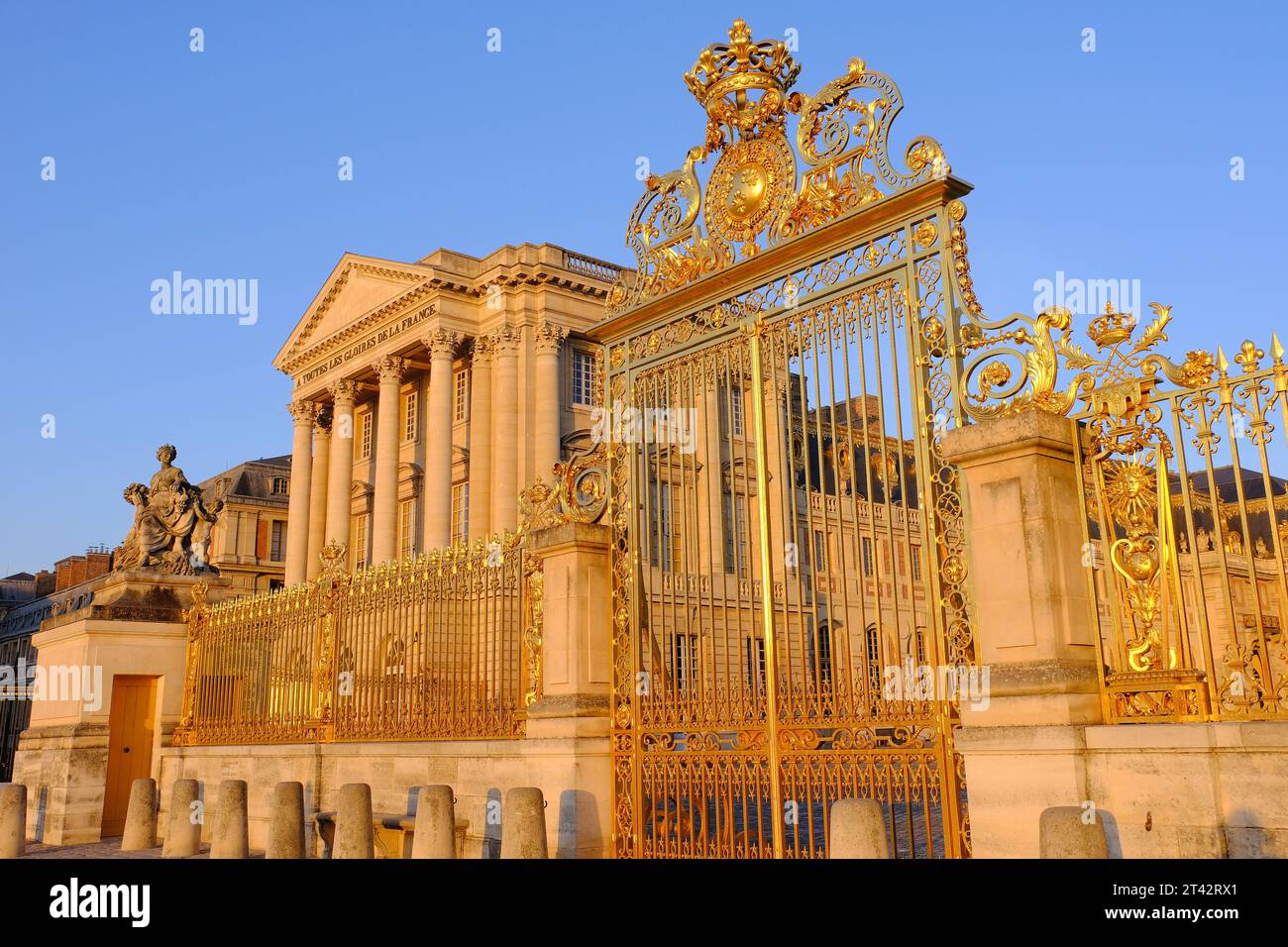 Versailles: Front face (East façade and courtyard) and entrance gate of the palace glowing orange just after sunrise at Versailles, Ile-de-France Stock Photo