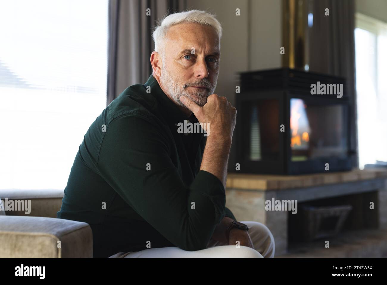 Portrait of thoughtful senior caucasian man sitting in armchair at home Stock Photo
