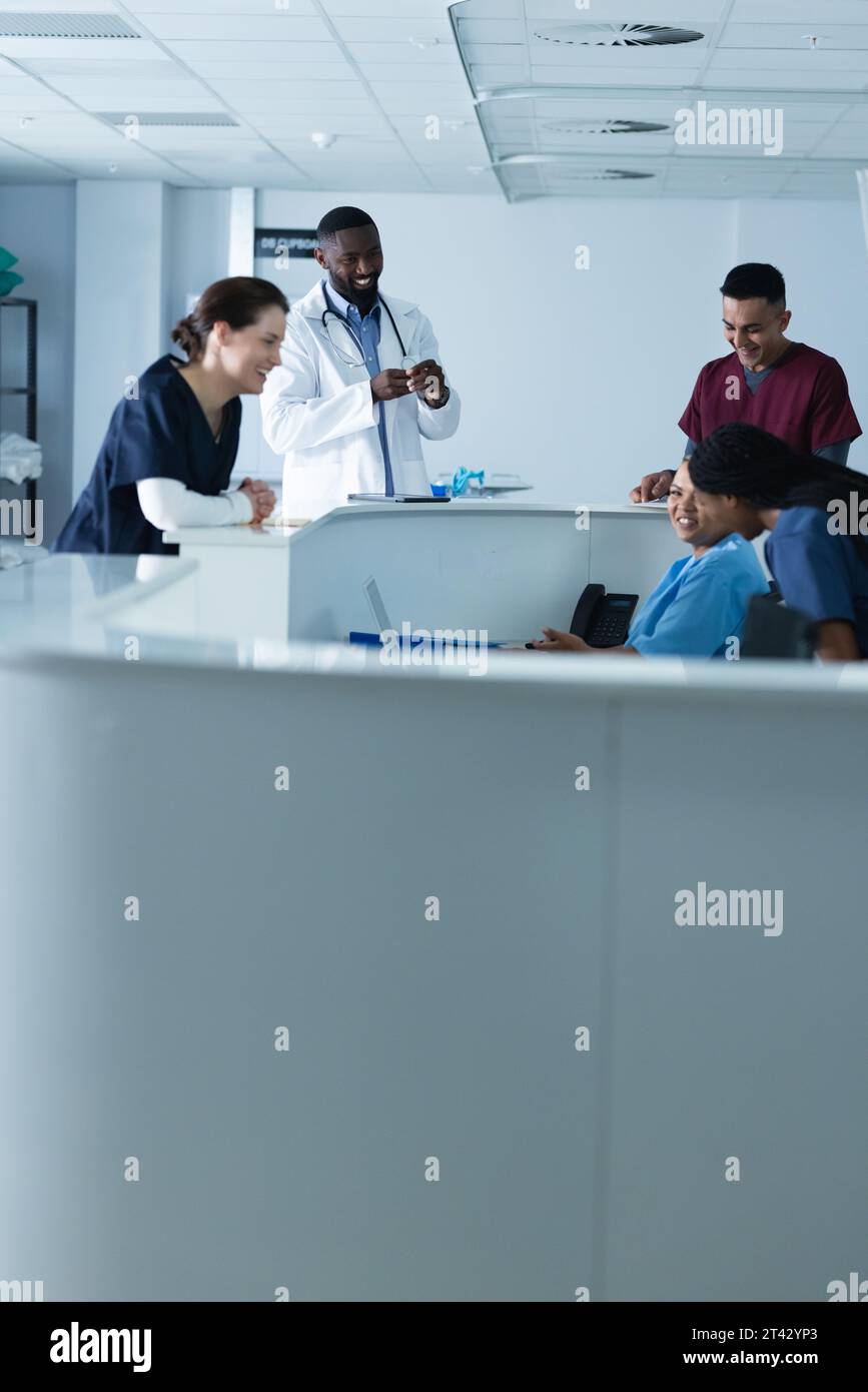 Happy diverse male and female doctors discussing work at reception desk at hospital Stock Photo