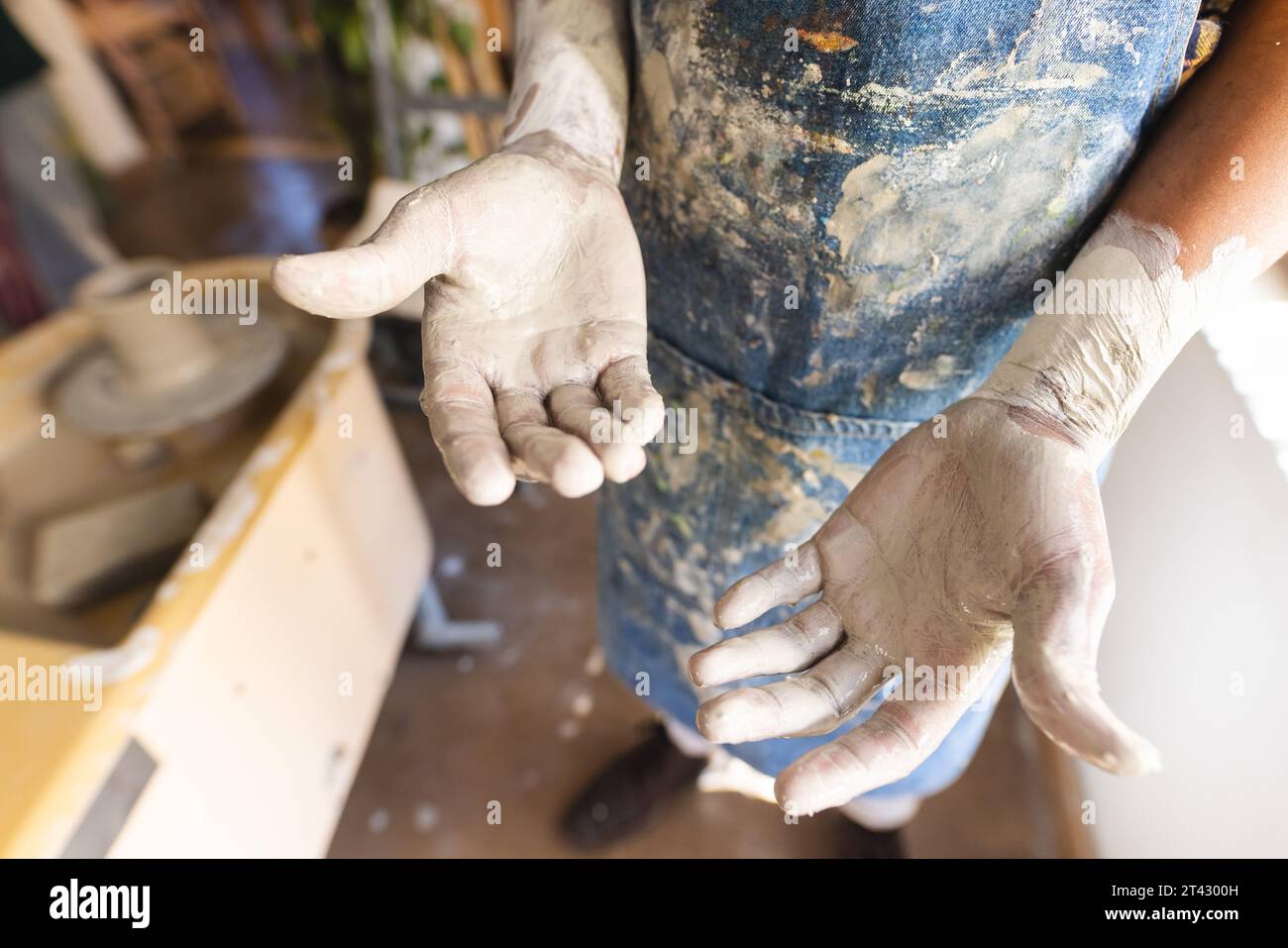 Dirty hands of african american potter standing in pottery studio Stock Photo