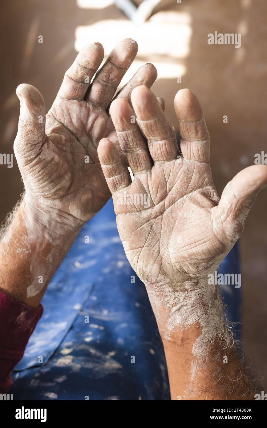Dirty hands of biracial senior potter sitting in pottery studio Stock Photo