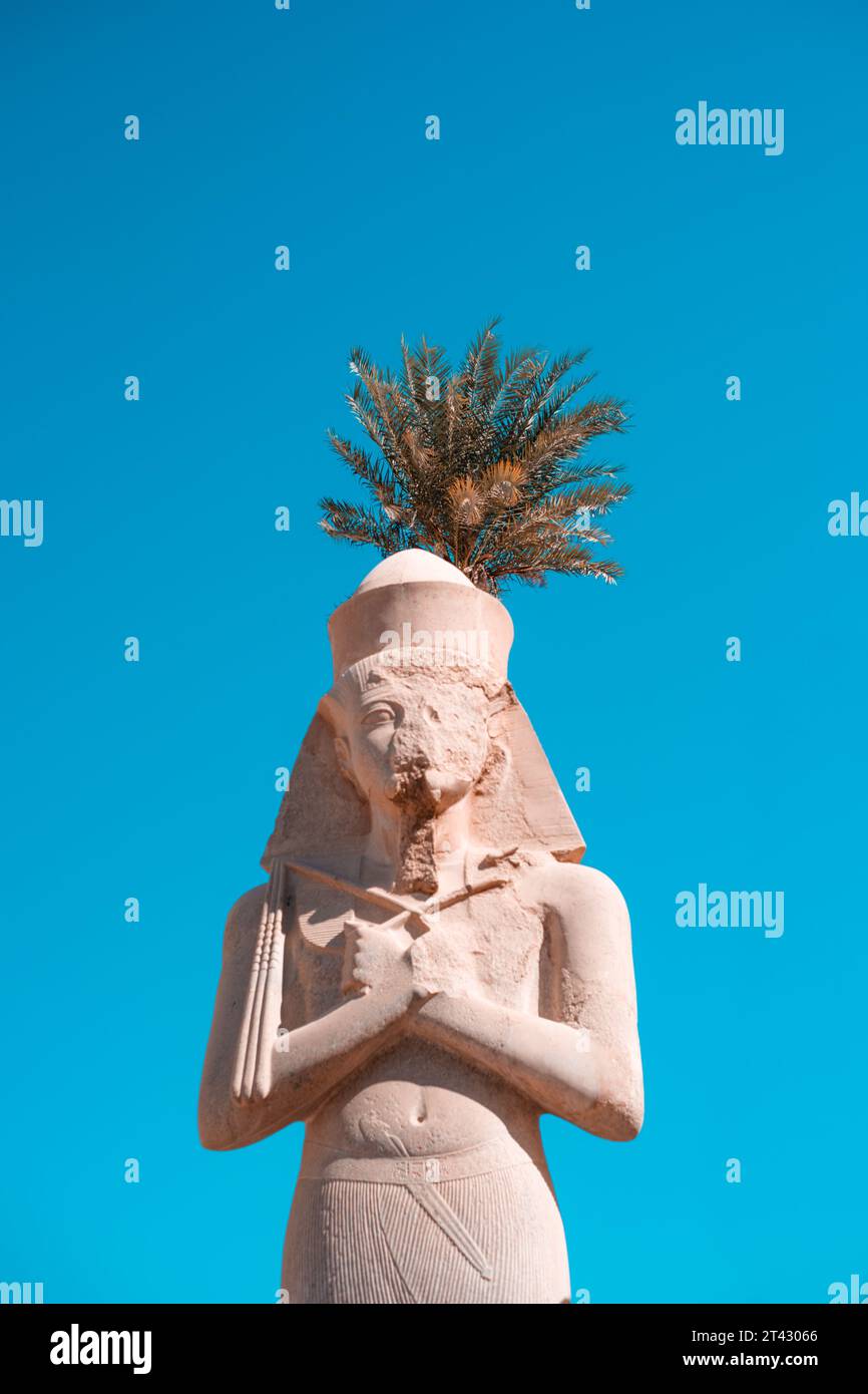 A palm-draped statue of a pharaoh at Luxor Temple Stock Photo - Alamy