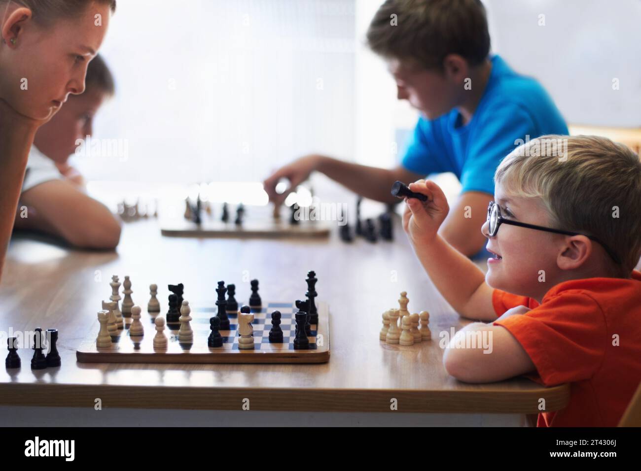 Students, chess and playing in a classroom, conversation and thinking with solution, problem solving and competition. Youth, group or boys with Stock Photo