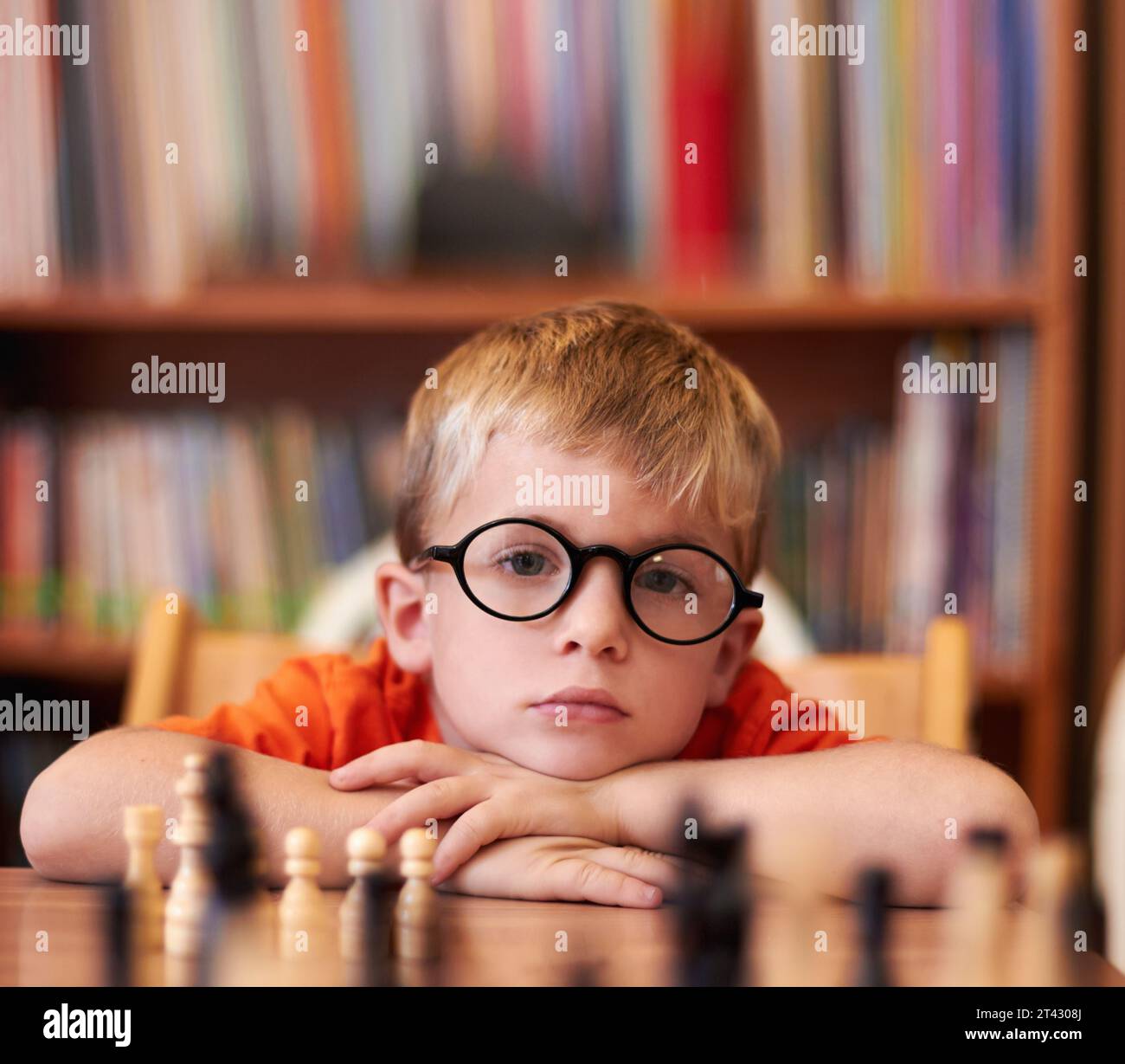Portrait, chess and boy with glasses, bored and competition with training, skills and clear vision. Face, person or kid with eyewear, tournament or Stock Photo