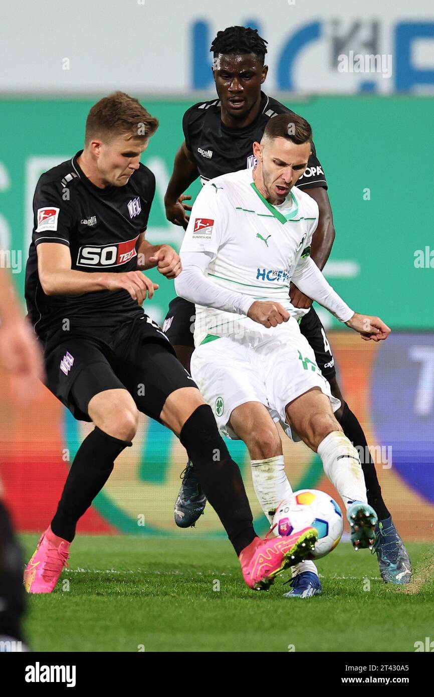 27 October 2023, Bavaria, Fürth: Soccer: 2. Bundesliga, SpVgg Greuther Fürth - VfL Osnabrück, Matchday 11 at Sportpark Ronhof Thomas Sommer. Fürth's Branimir Hrgota (r) fights for the ball with Lukas Kunze (l) and Osnabrück's Maxwell Gyamfi. Photo: Daniel Karmann/dpa - IMPORTANT NOTE: In accordance with the requirements of the DFL Deutsche Fußball Liga and the DFB Deutscher Fußball-Bund, it is prohibited to use or have used photographs taken in the stadium and/or of the match in the form of sequence pictures and/or video-like photo series. Stock Photo