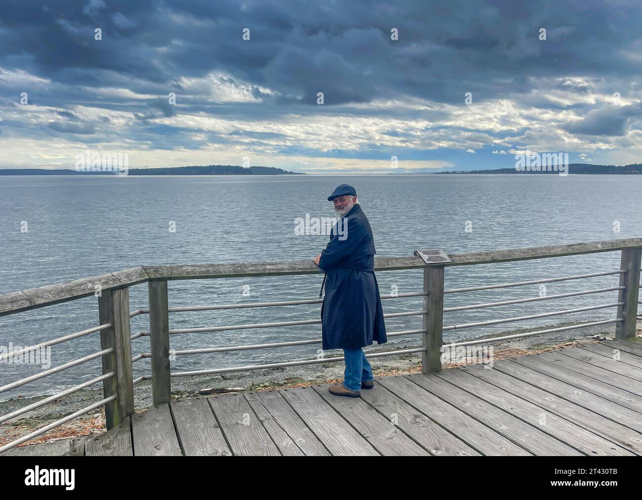 Man standing on a jetty looking out to sea on an overcast day, Sidney, British Columbia, Canada Stock Photo