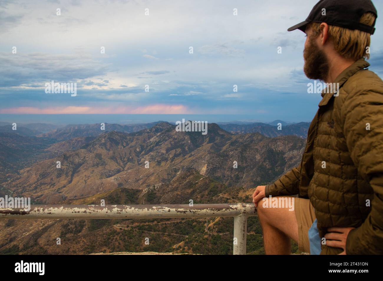 Man standing by railings looking at distant village in mountain valley, Sequoia National Park, California, USA Stock Photo