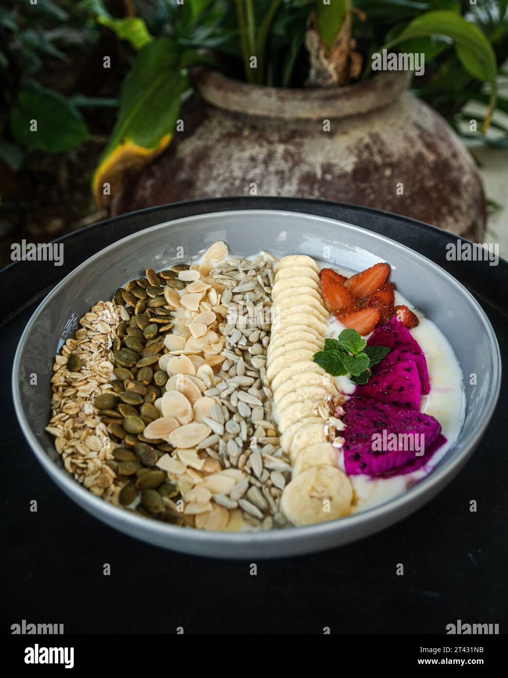 Close-up of a bowl of yogurt with fresh strawberries, dragon fruit, bananas, nuts and seeds Stock Photo