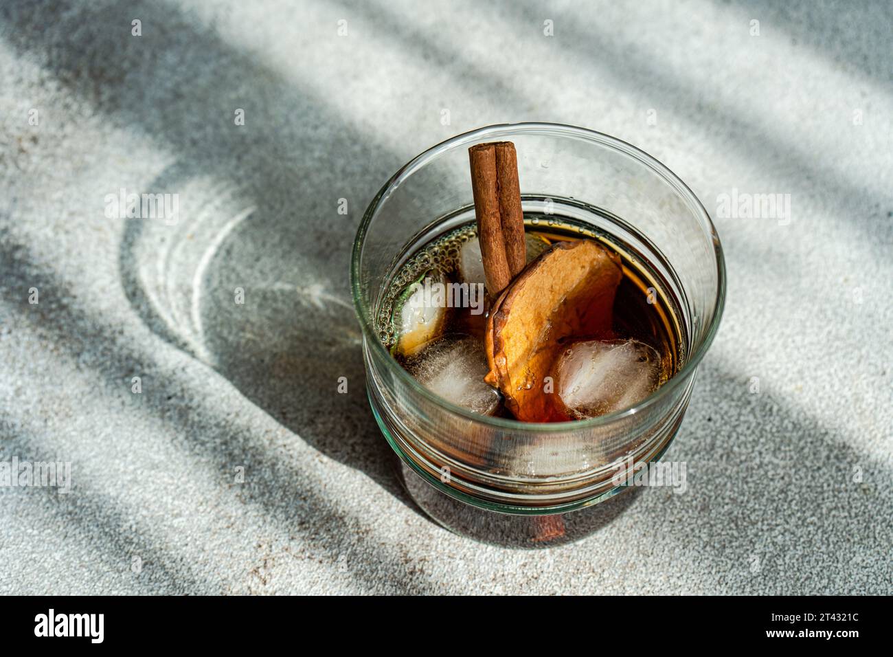 Apple cider cocktail with dried apple slices and a cinnamon stick on a table Stock Photo