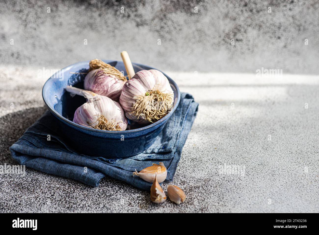 Close-up of fresh garlic bulbs and garlic cloves in a bowl with a napkin Stock Photo