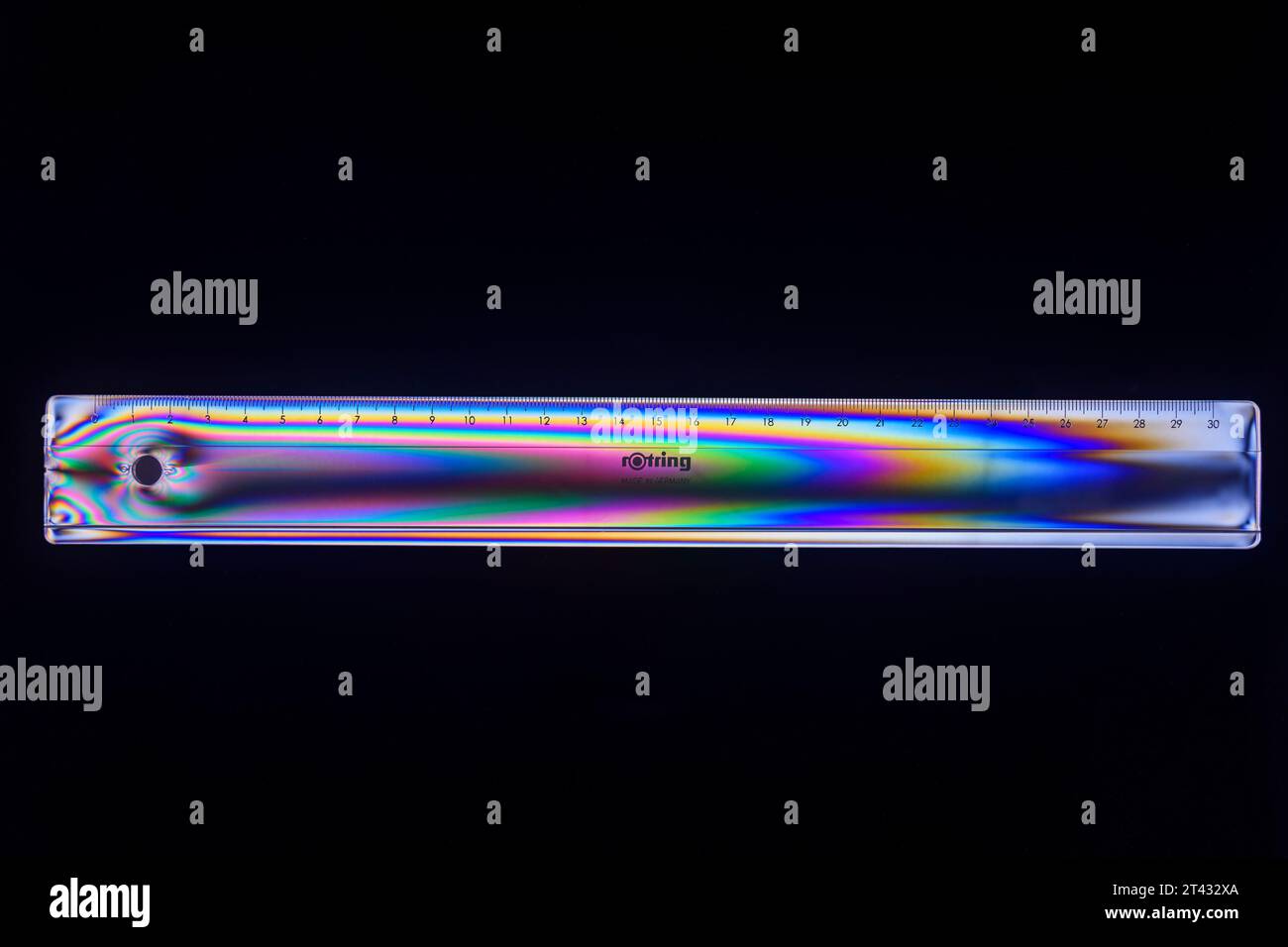 Rotring clear plastic 30cm ruler viewed between crossed polarising filters. Stock Photo