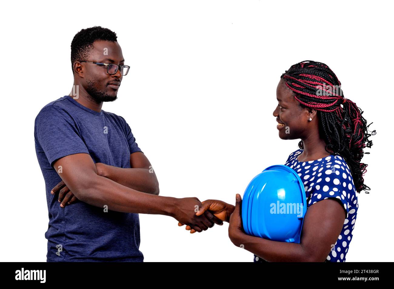 young man shaking hands with young female construction engineer while smiling. Stock Photo