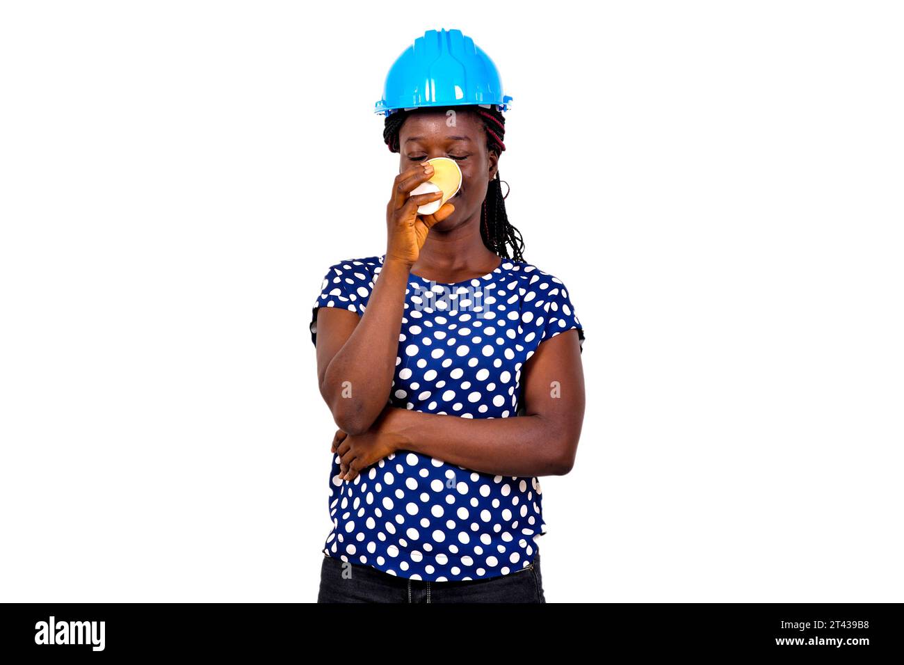 portrait of a beautiful young female construction engineer wearing a blue hard hat drinking coffee from a paper cup. Stock Photo