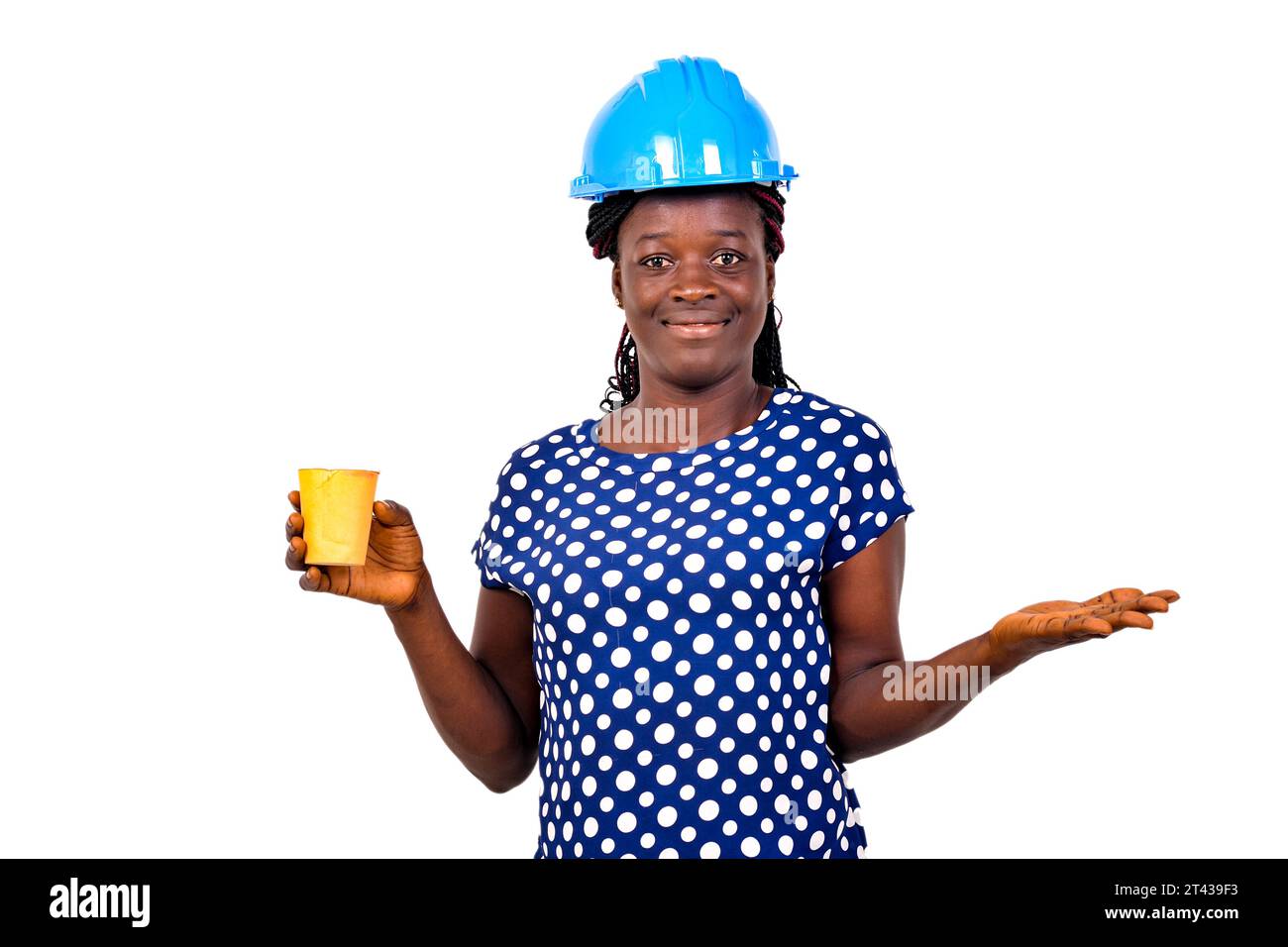 young female construction engineer wearing a blue hard hat holding a paper coffee cup and gesturing her hand. Stock Photo