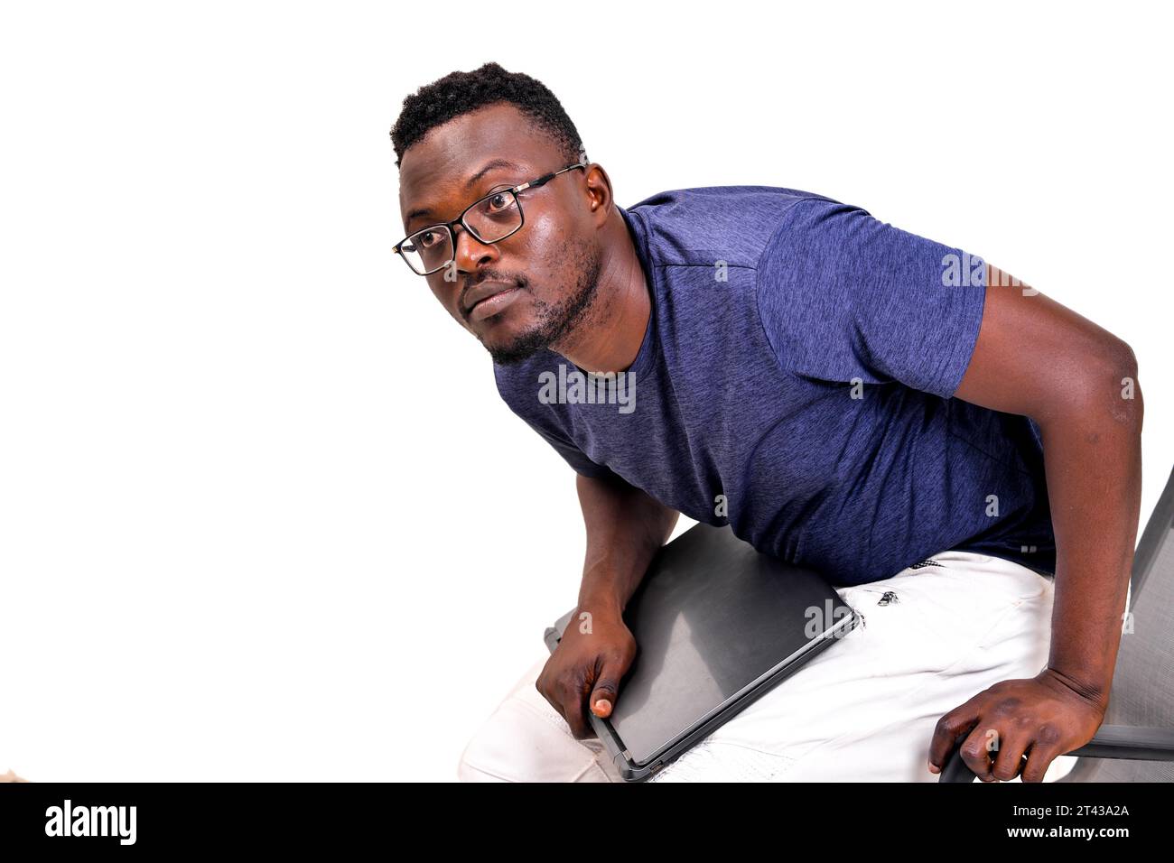 portrait of a young businessman wearing his optical glasses and sitting on a chair with the laptop. Stock Photo