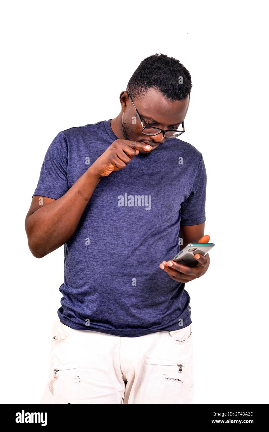 young man in blue t-shirt standing on white background looking at cellphone and pointing finger. Stock Photo