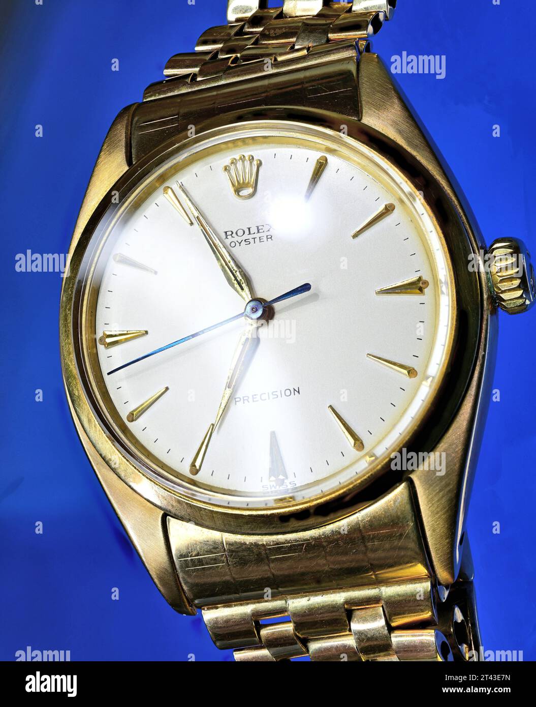 Gold Rolex Oyster wristwatch against a deep blue background Stock Photo