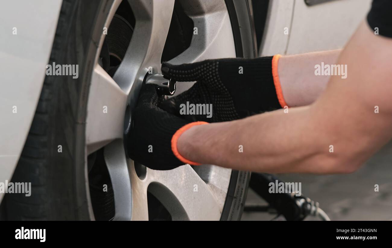 Mechanic Repairs Car, Working Diligently To Unscrew Wheel Bolt Stock