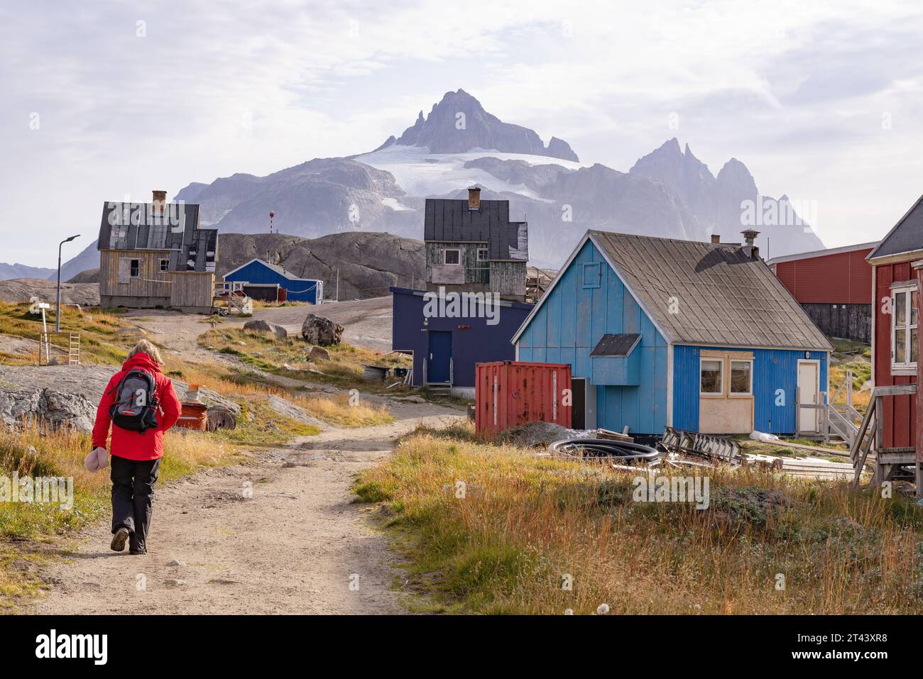Greenland tourist walking between houses in the small isolated inuit village of Aappilattoq, pop. 100; South Greenland. Arctic Travel. Stock Photo