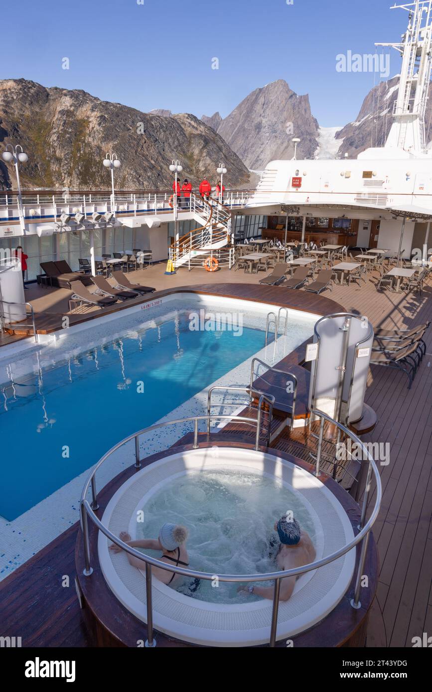 Greenland tourism; tourist couple enjoying the Jacuzzi on an arctic cruise, cruising with Silversea cruise Line on the Silver Cloud ship, Greenland. Stock Photo