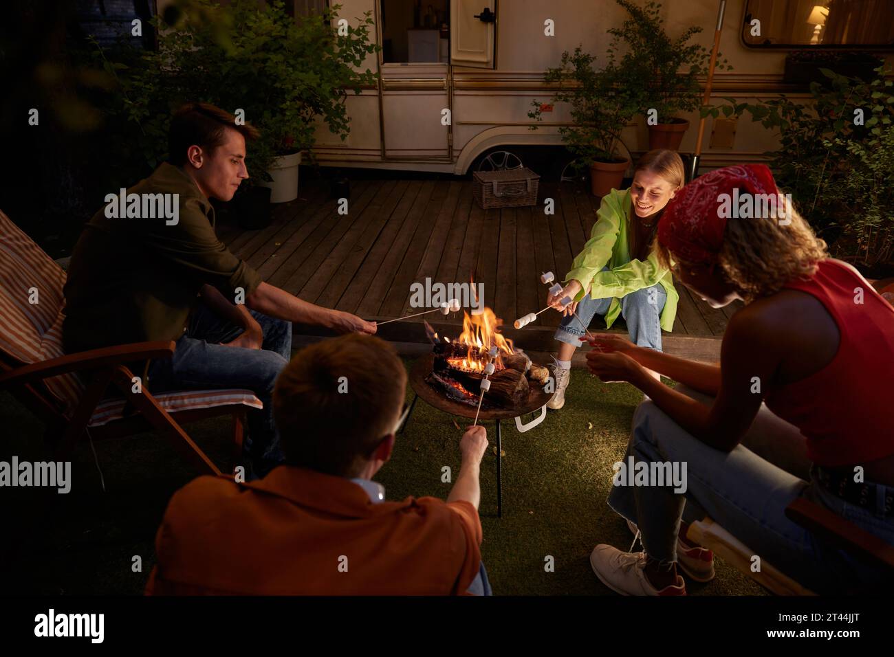 Happy group of teen friends roasting marshmallows at campfire Stock Photo