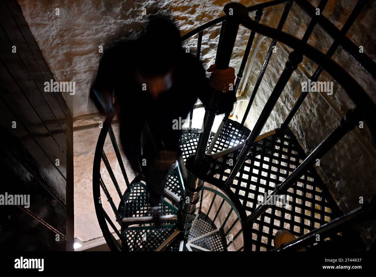 Looking down spiral metal staircase with silhouette of blurred indistinct person in bell town of historic church tower Stock Photo