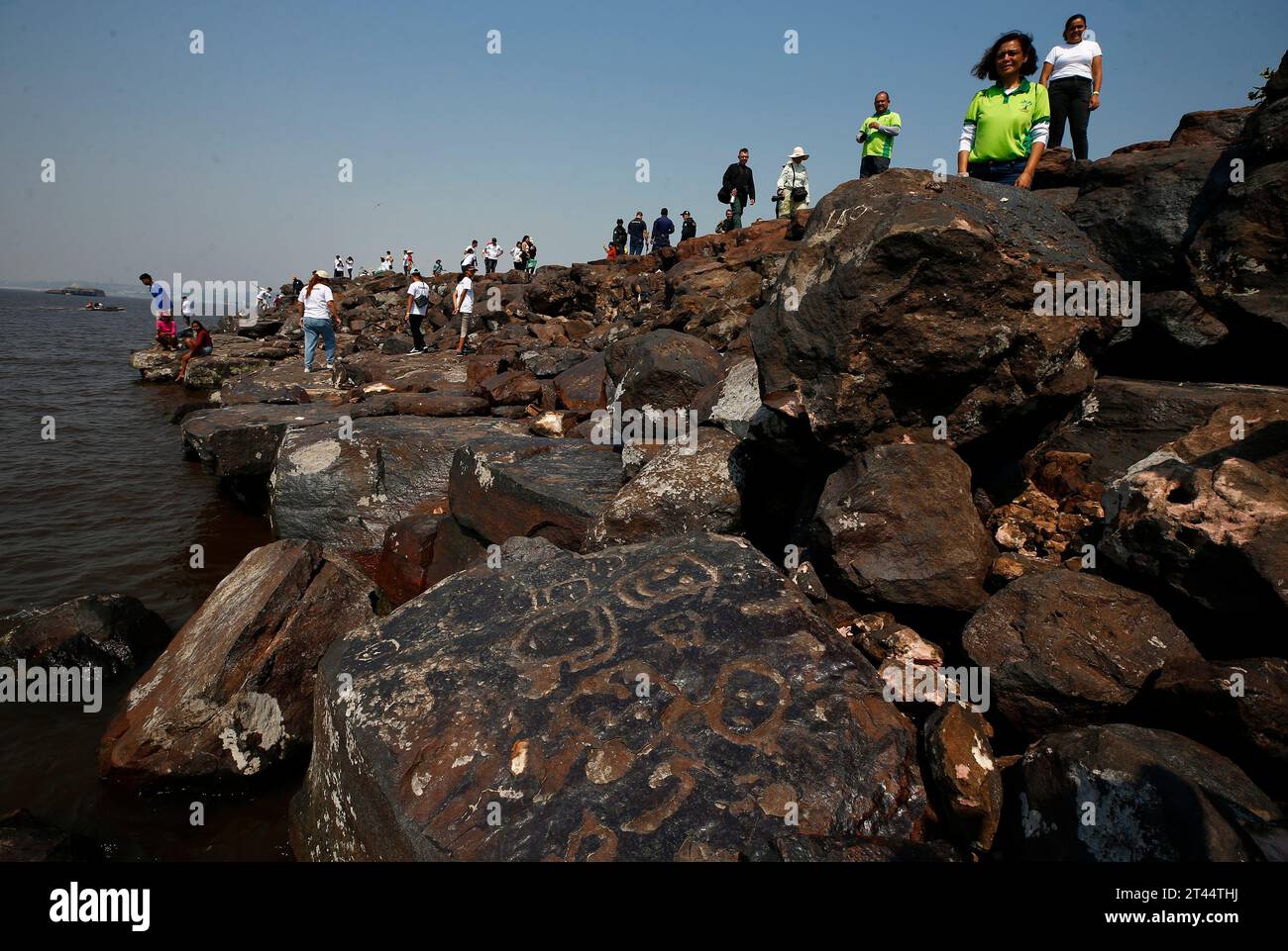 Archaeologists and residents gather around rock paintings at the Ponta ...
