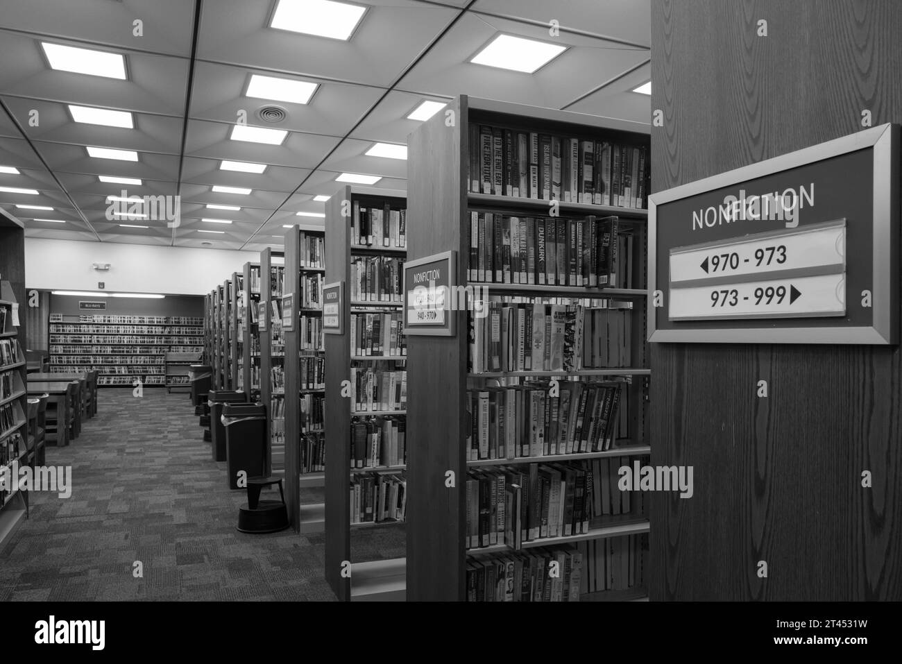 A public library with books on shelves and signs indicating categories