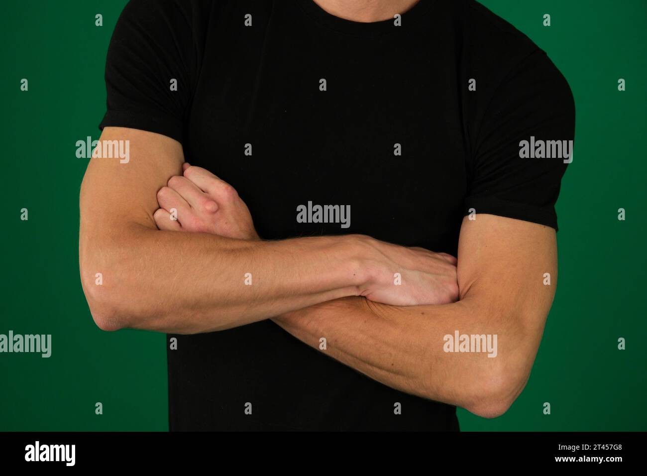 guy on a green background chromakey close-up dark hair young man. pumped up arms in a black T-shirt, recognizable peopl Stock Photo