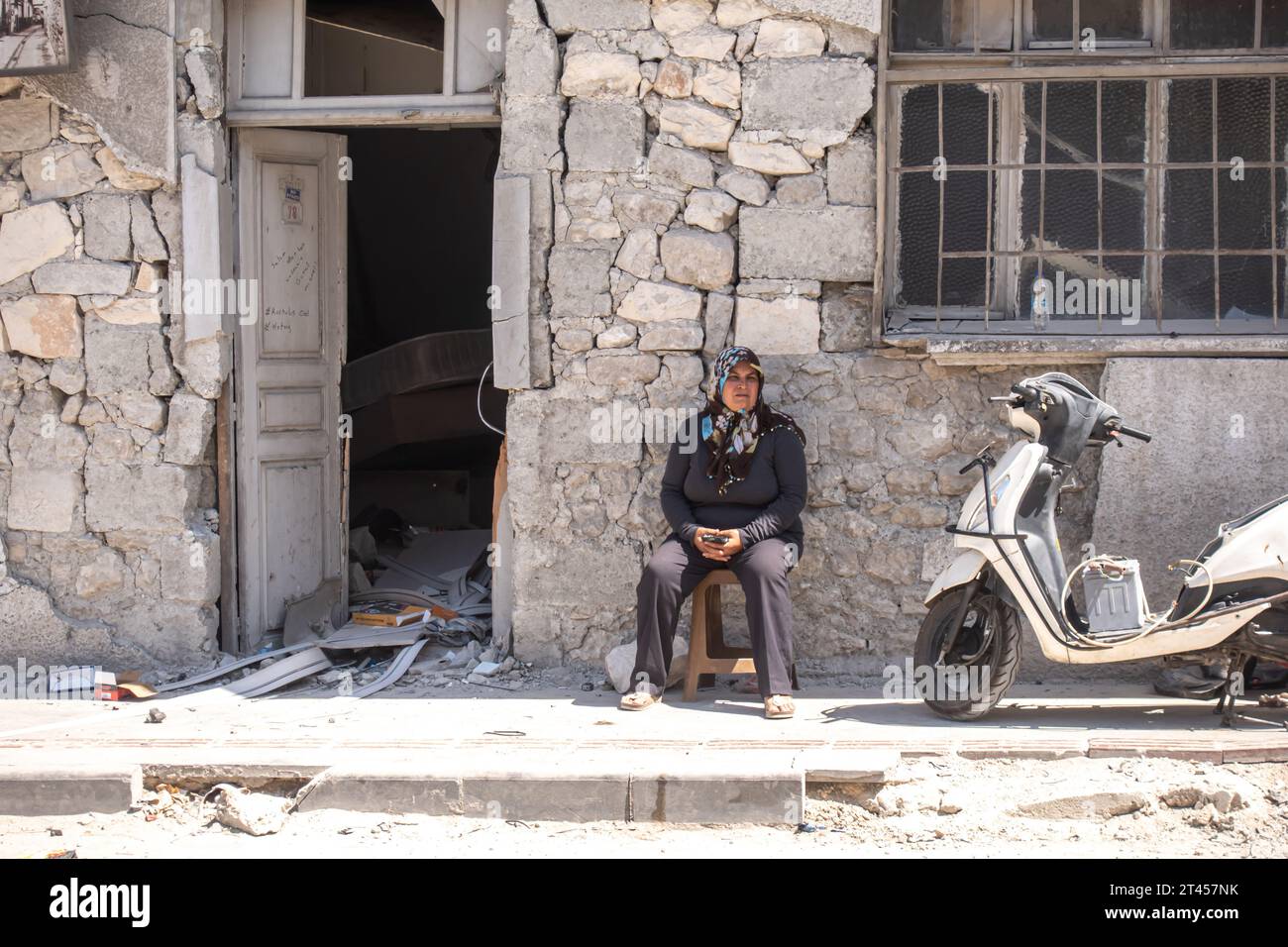 A Turkish woman sits by the house in Antakya central historic street hit by Turkish Earthquake 2023, Hatay Turkey Stock Photo