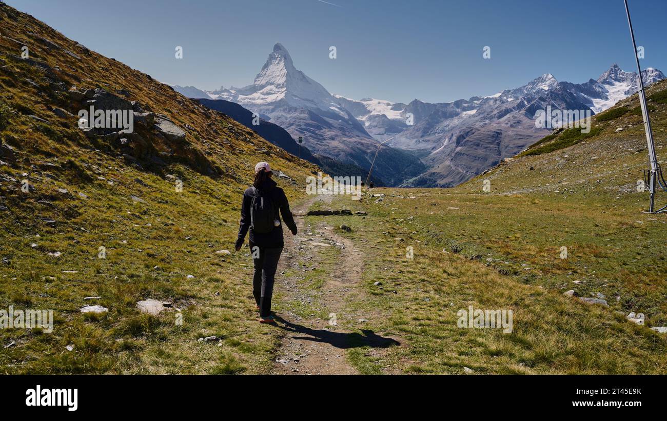 Young woman hiker on a hiking trail towards the Matterhorn peak in ...