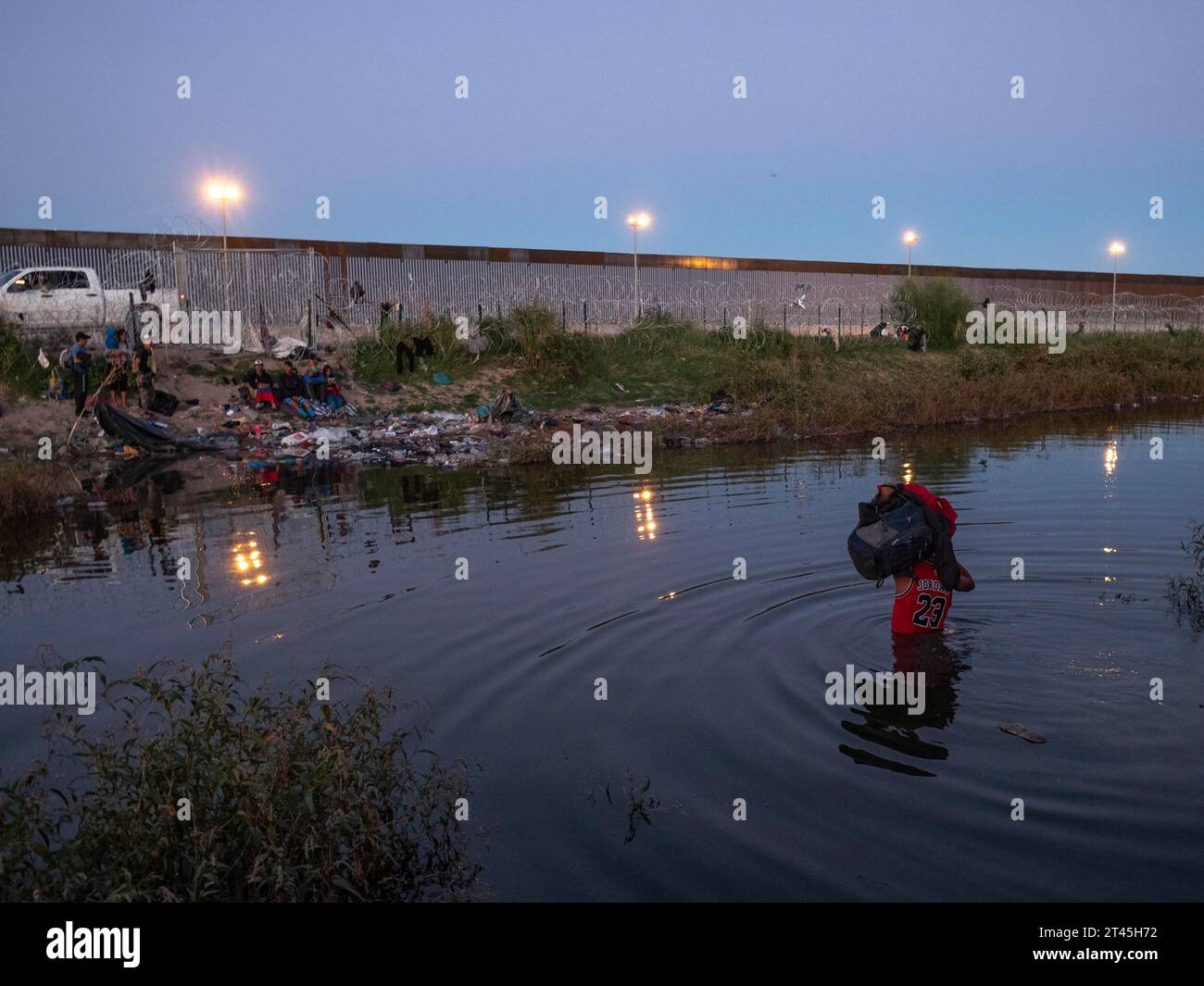 Ciudad Juarez, Chichuahua, Mexico. 26th Oct, 2023. Migrants, mostly Venezuelans, go from Mexican soil across a narrow waterway to reach land just outside of the United States border. They hope that the nearby gate 36 will open and allow them to apply for asylum. Many of those crossing are young families with young children. The U.S border patrol waits on the other side behind the fence, mostly denying entry. (Credit Image: © Sue Dorfman/ZUMA Press Wire) EDITORIAL USAGE ONLY! Not for Commercial USAGE! Stock Photo