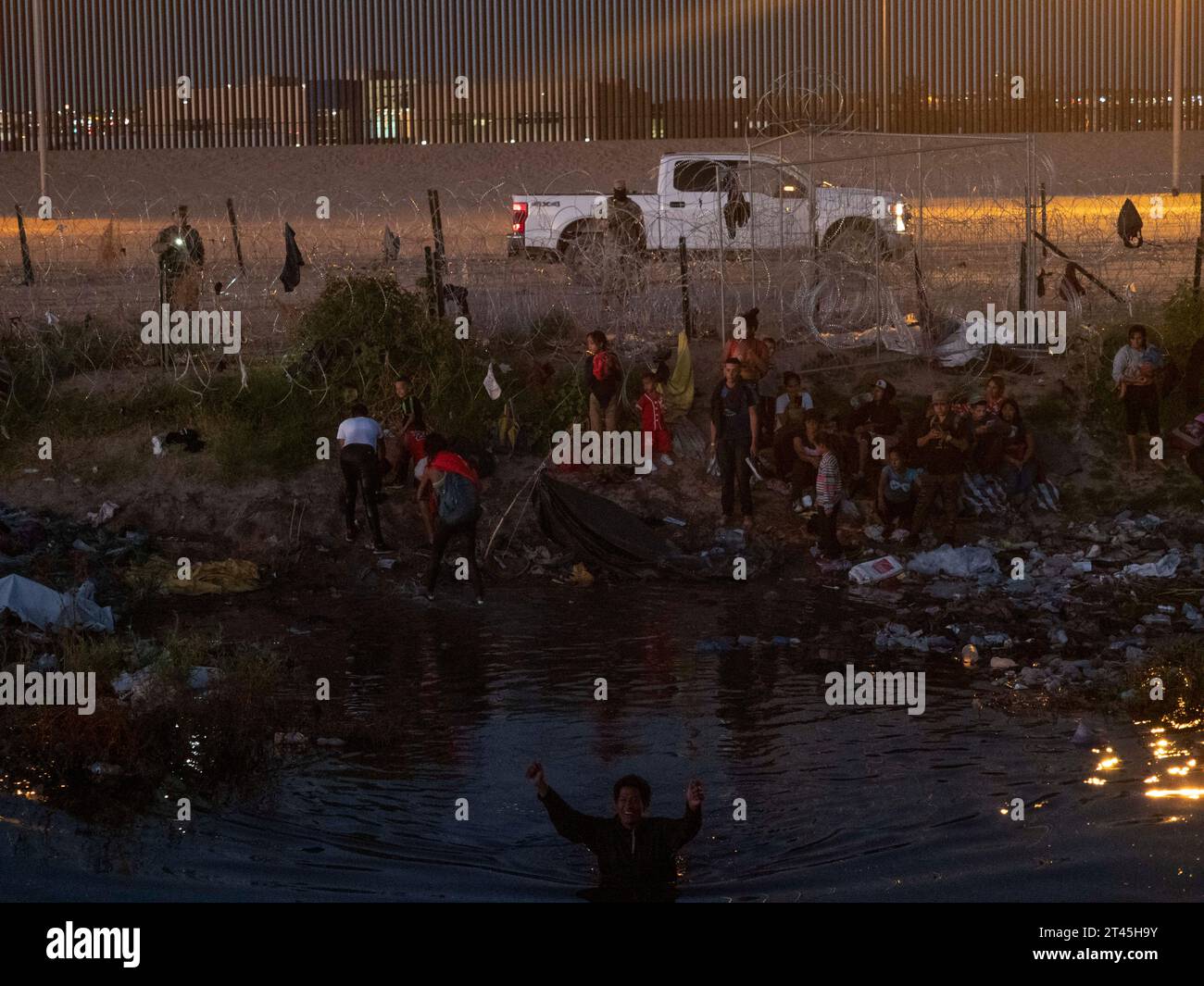 Ciudad Juarez, Chichuahua, Mexico. 26th Oct, 2023. Migrants, mostly Venezuelans, go from Mexican soil across a narrow waterway to reach land just outside of the United States border. They hope that the nearby gate 36 will open and allow them to apply for asylum. Many of those crossing are young families with young children. The U.S border patrol waits on the other side behind the fence, mostly denying entry. (Credit Image: © Sue Dorfman/ZUMA Press Wire) EDITORIAL USAGE ONLY! Not for Commercial USAGE! Stock Photo