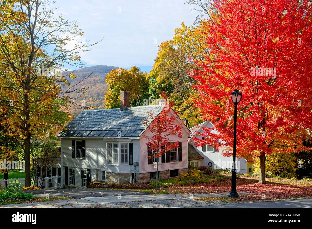 Colonial houses surrounded by brightly lit autumn trees with colorful Taconic mountains behind — Bennington, Vermont, October 2023 Stock Photo