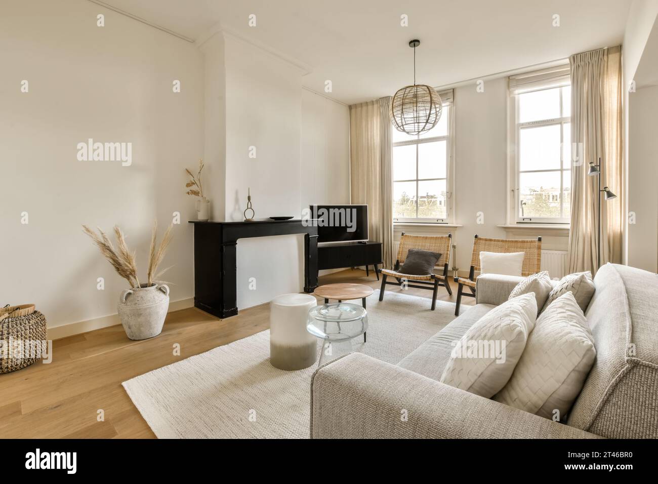 a living room with white walls and wood flooring, including a black ...