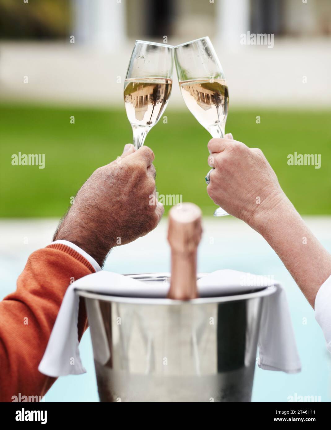 Champagne, toast and hands of senior couple at a hotel for travel, freedom or romantic adventure. Wine, cheers and elderly people with poolside Stock Photo