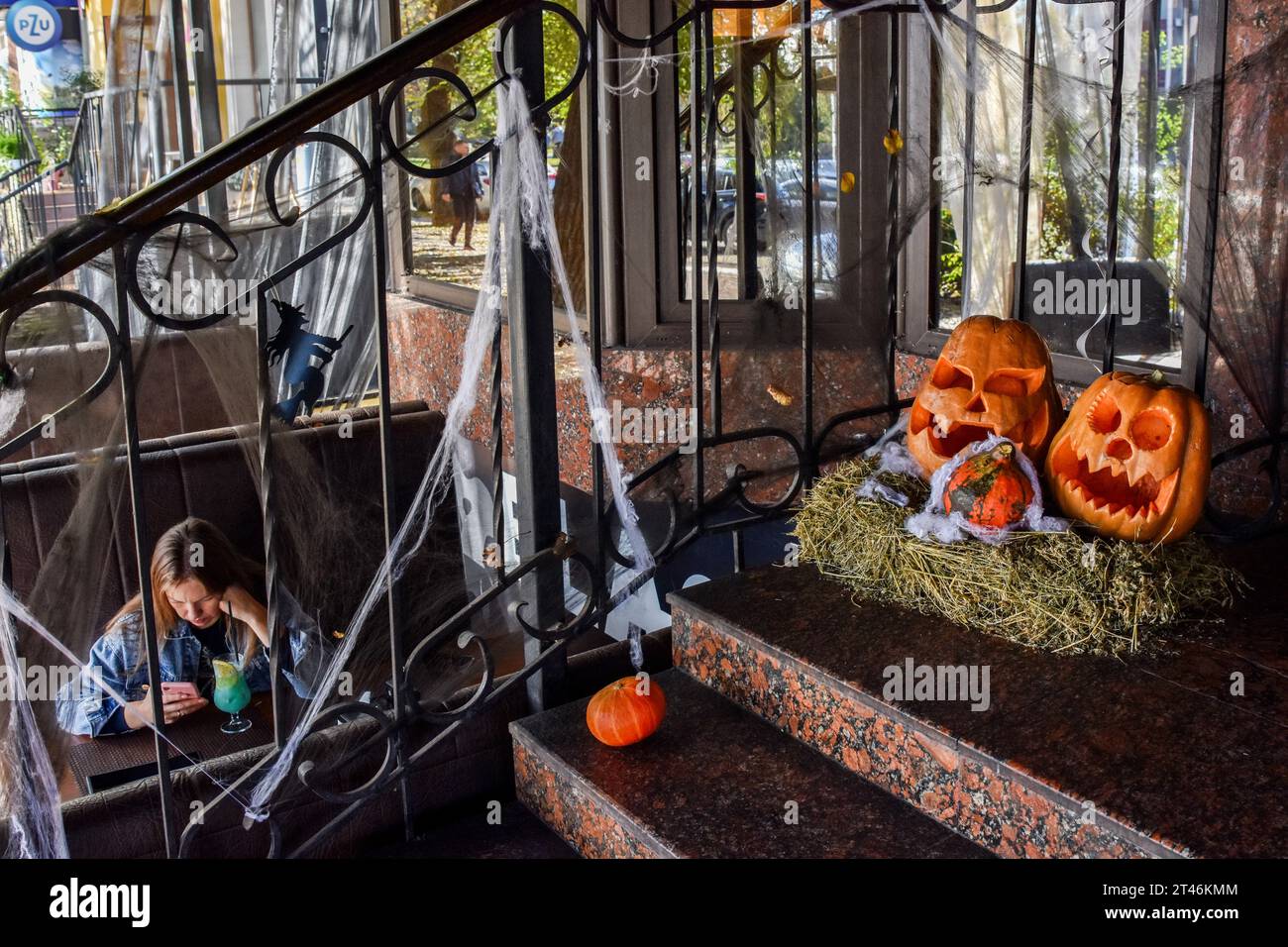Halloween decorations are seen placed at the café entrance in Zaporizhzhia. Halloween of Celtic origin came to Ukraine after the collapse of the Soviet Union. From that time the Ukrainians took over the tradition from other countries to dress in creepy costumes, to cut out the main attribute of this holiday - the pumpkin and to collect the candies among the neighbors. The modern Orthodox Church is still condemning this holiday, but every year in Ukraine are more and more young people who aren't against “going to the side of the evil” for one night. Stock Photo