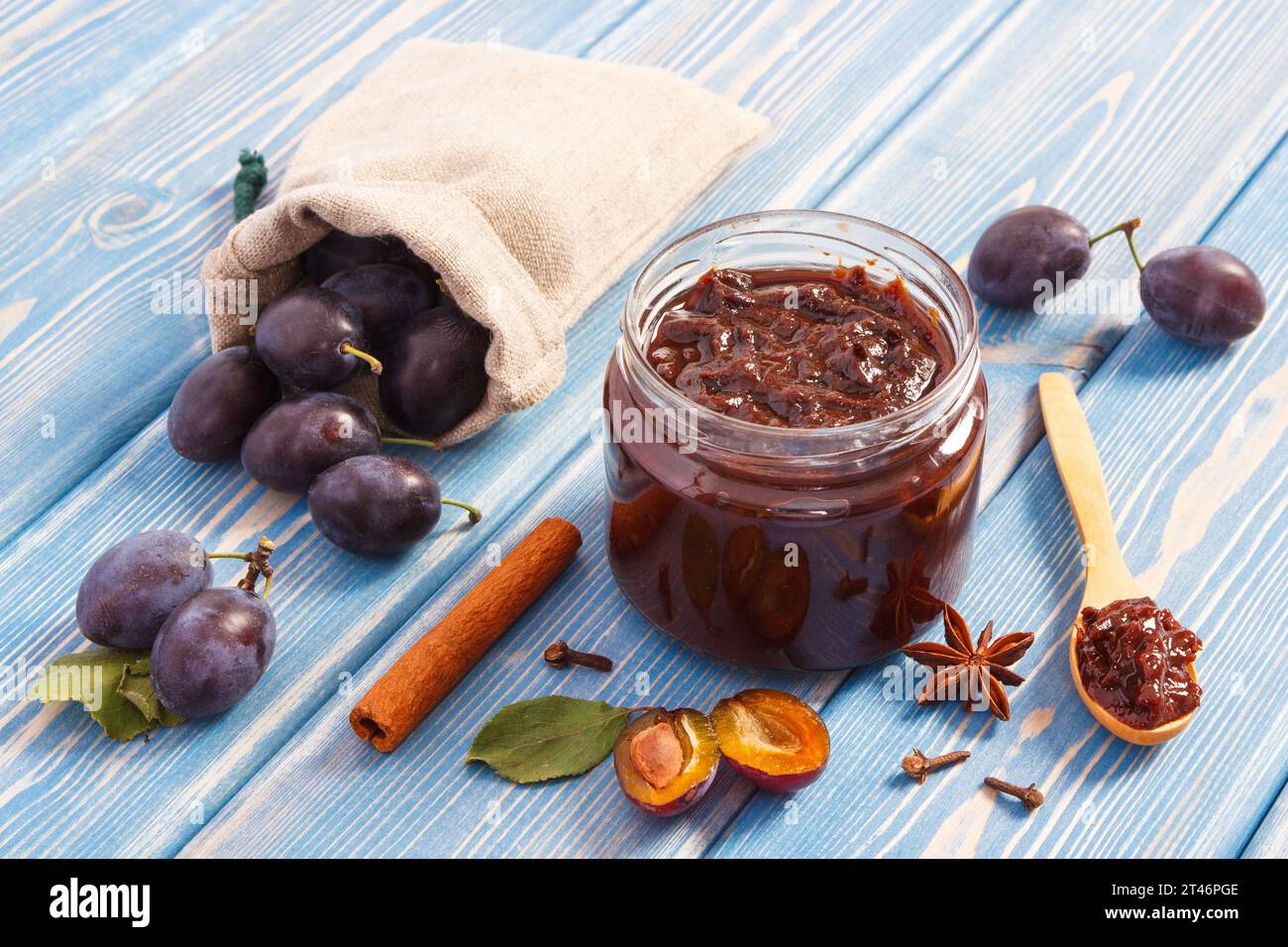 Fresh plum jam or marmalade in glass jar, ripe fruits and spices on boards, concept of healthy sweet dessert Stock Photo
